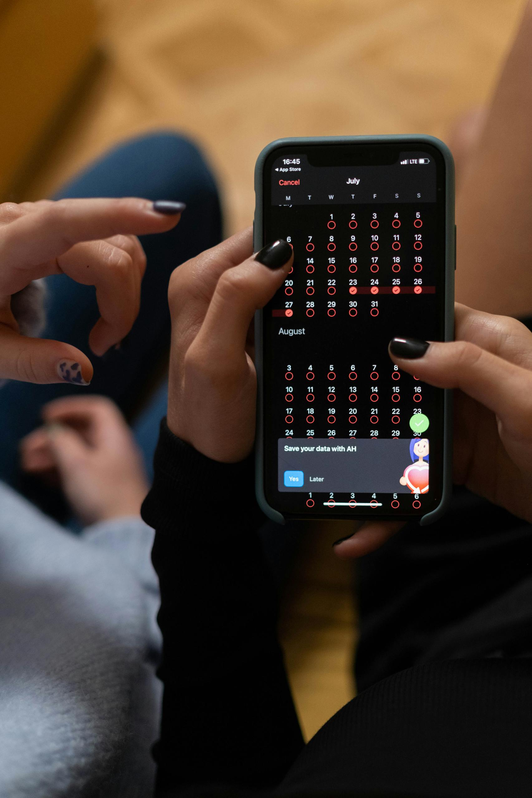 Close-up of hands interacting with a smartphone displaying a digital calendar app.